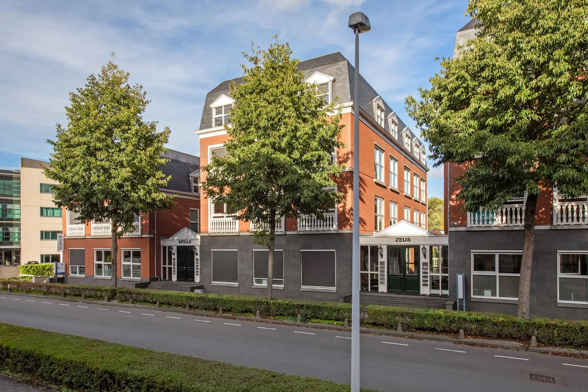 Kantoorgebouwen Apollo en Zeus aan de Laan van Vredenoord, omgeven door bomen en gelegen aan een rustige weg.